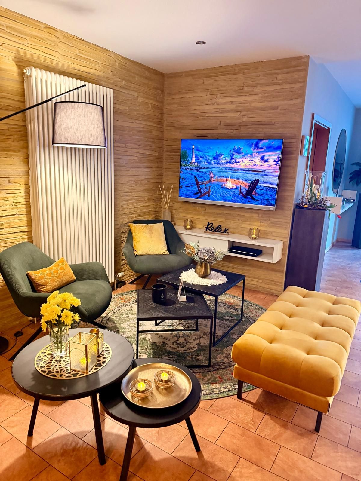 Gemütliche Lounge-Ecke mit grünen Sesseln, gelbem Hocker und warmer Beleuchtung