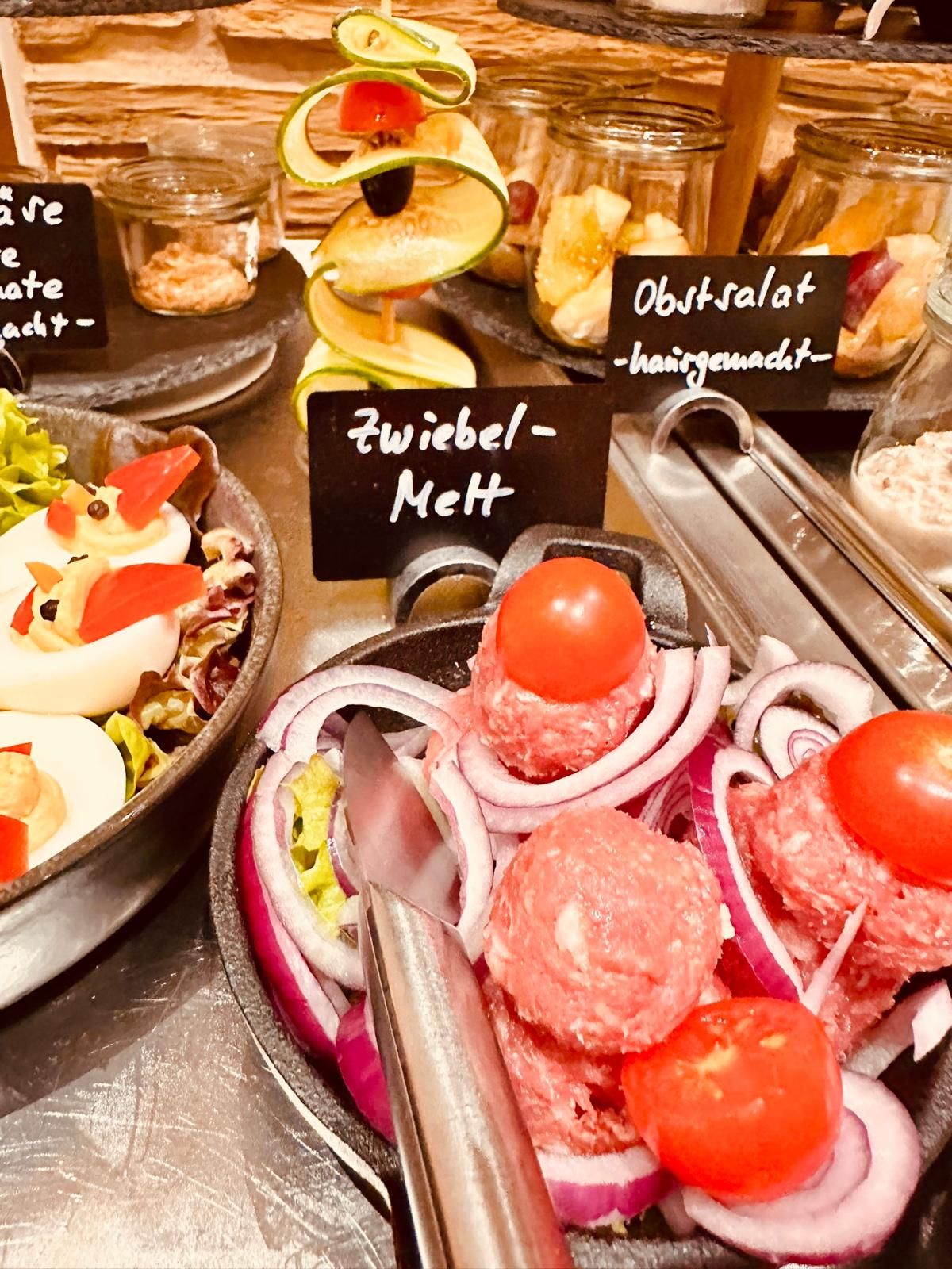 Zwiebelmett mit roten Zwiebeln und Cherry-Tomaten am Frühstücksbuffet