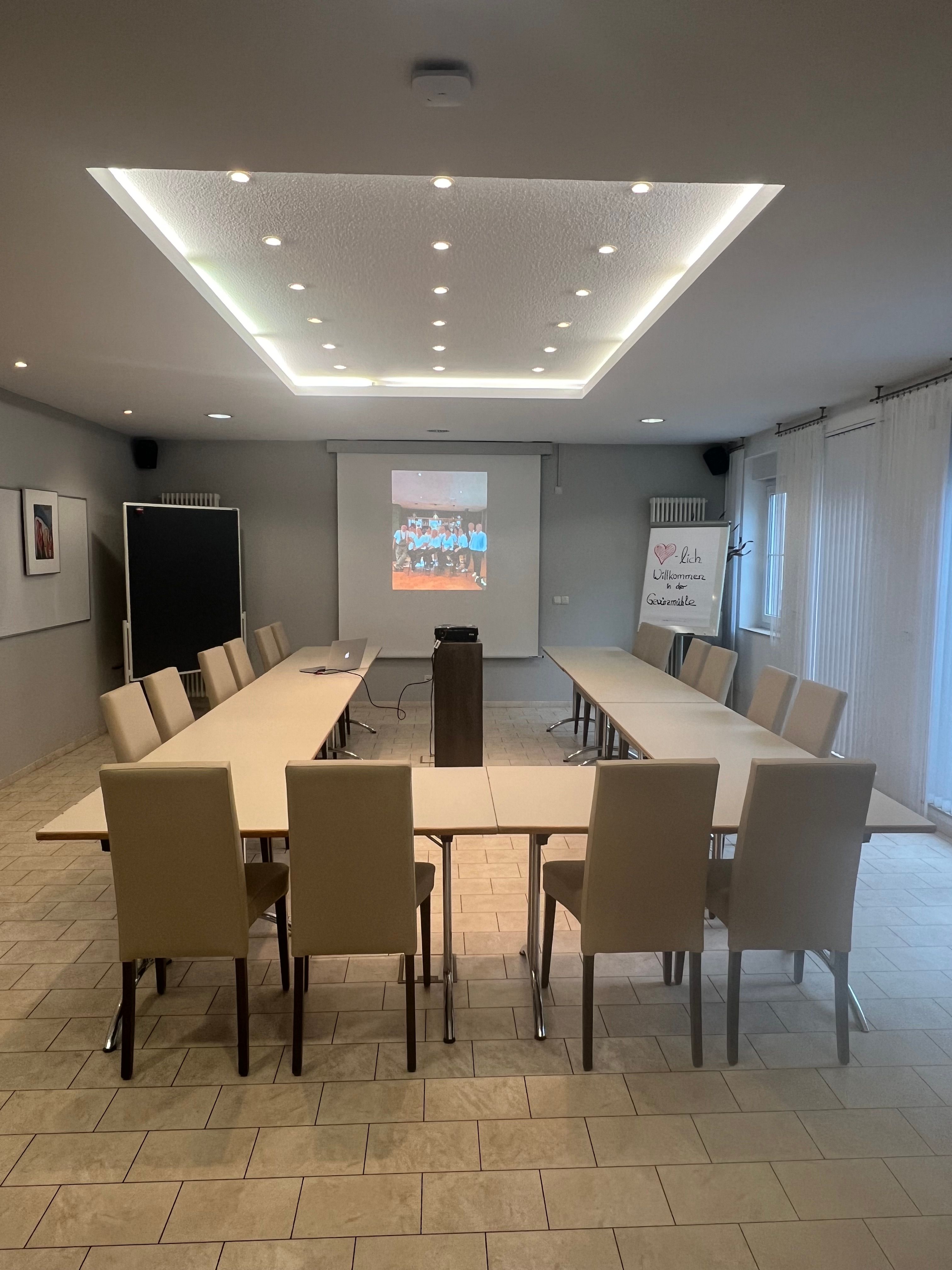 Tagungsraum mit Beamer-Projektion und U-Form-Bestuhlung