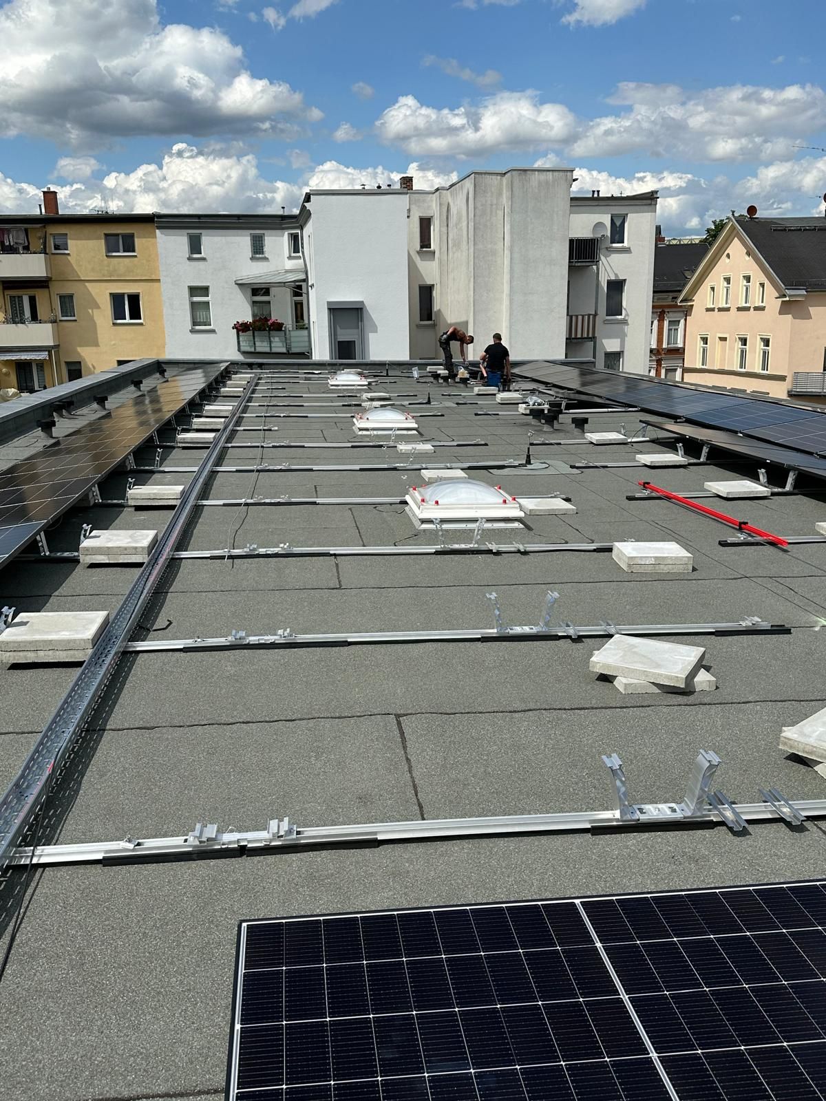 Blick über die Solar-Module — Module komplett montiert, Stadtpanorama im Hintergrund