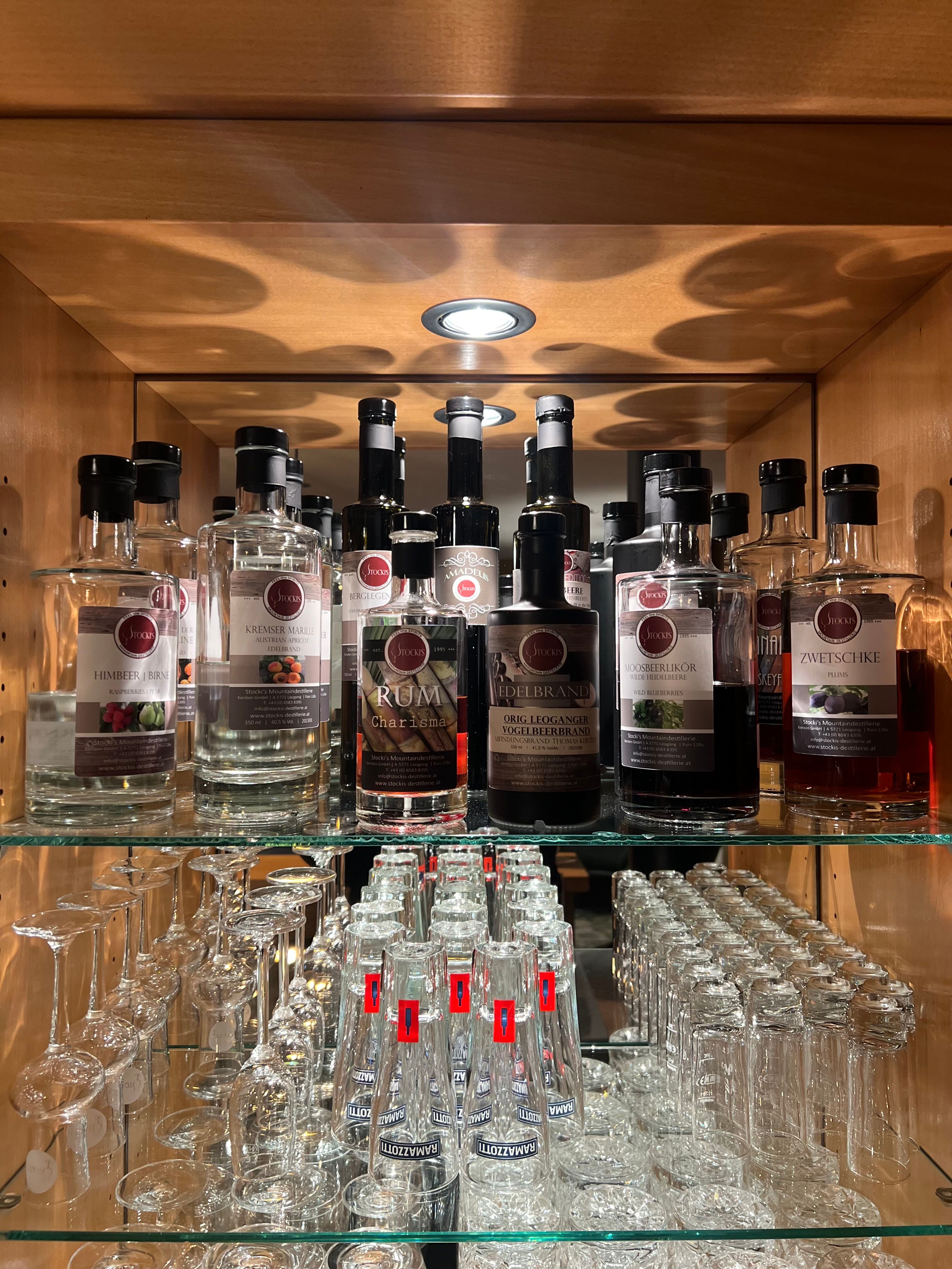 Beleuchtete Vitrine mit Stocki's Edelbränden aus Leogang — Kremser Marille, Rum Charisma, Vogelbeerbrand, Moosbeerlikör und Zwetschke