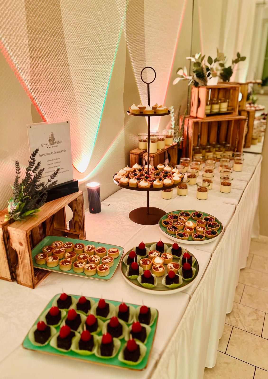 Sweet Table mit Tartelettes, Brownies und Verrines vor LED-beleuchteter Wand